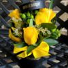 A bouquet of yellow roses in a black vase.