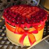 A large round box of roses on top of a table.