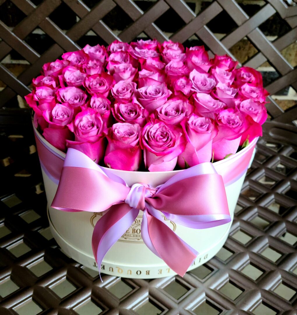 A white hat box filled with pink roses.