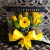 A yellow flower arrangement in a box with a bow.