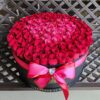 A large round box of roses on top of a table.