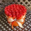 A bouquet of roses in a box on top of a table.