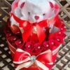 A red and white teddy bear in a hat box