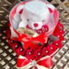 A white teddy bear sitting in a box with red roses.