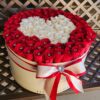 A large red and white flower arrangement in a round box.